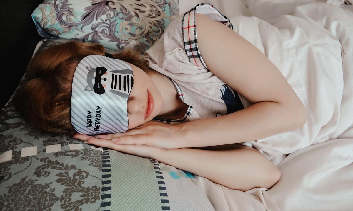 A blackout sleep mask resting on a bed