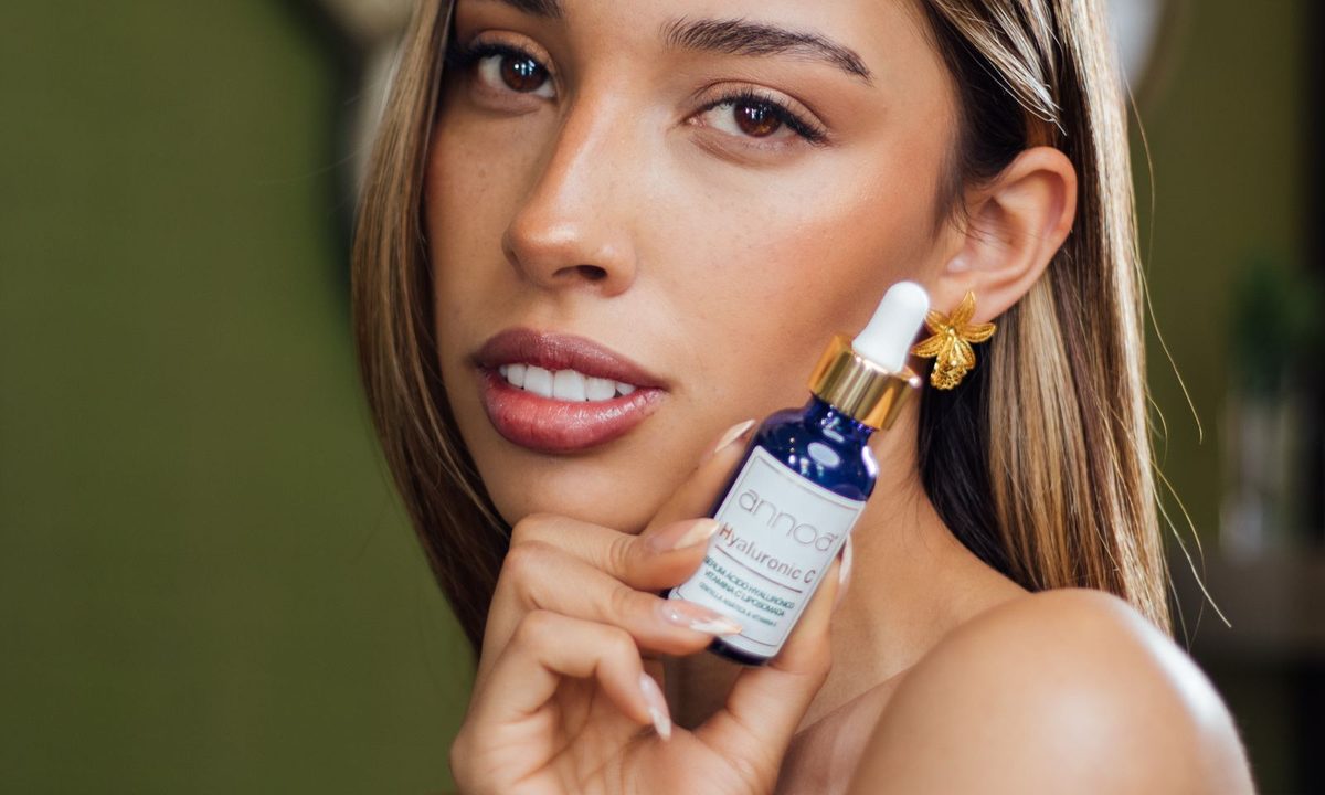 A hand holding a hyaluronic acid serum bottle